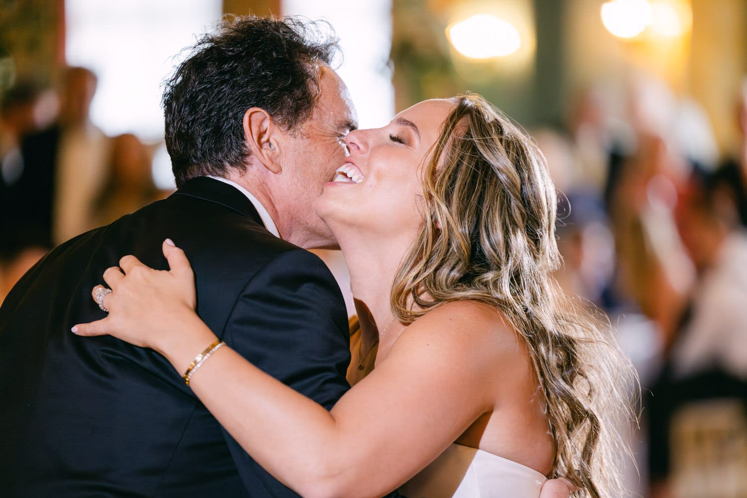 A joyful bride shares an emotional embrace with her father during their dance at a wedding celebration.