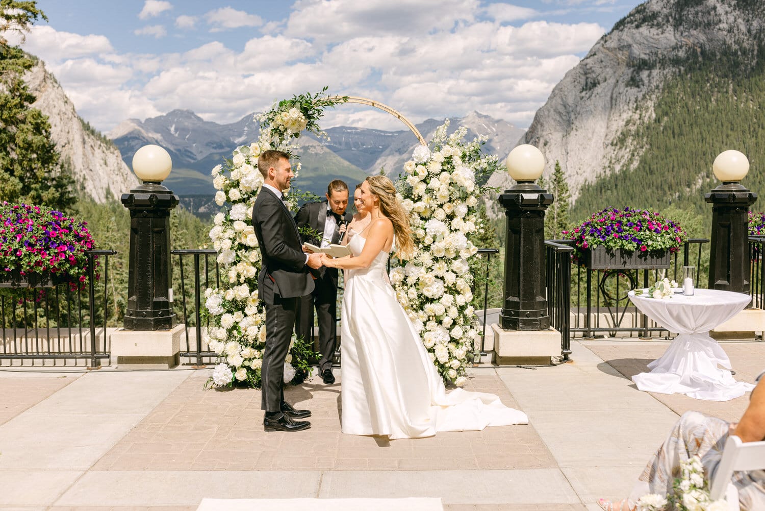 A couple exchanges vows during their wedding ceremony, surrounded by beautiful floral decor and stunning mountain views.