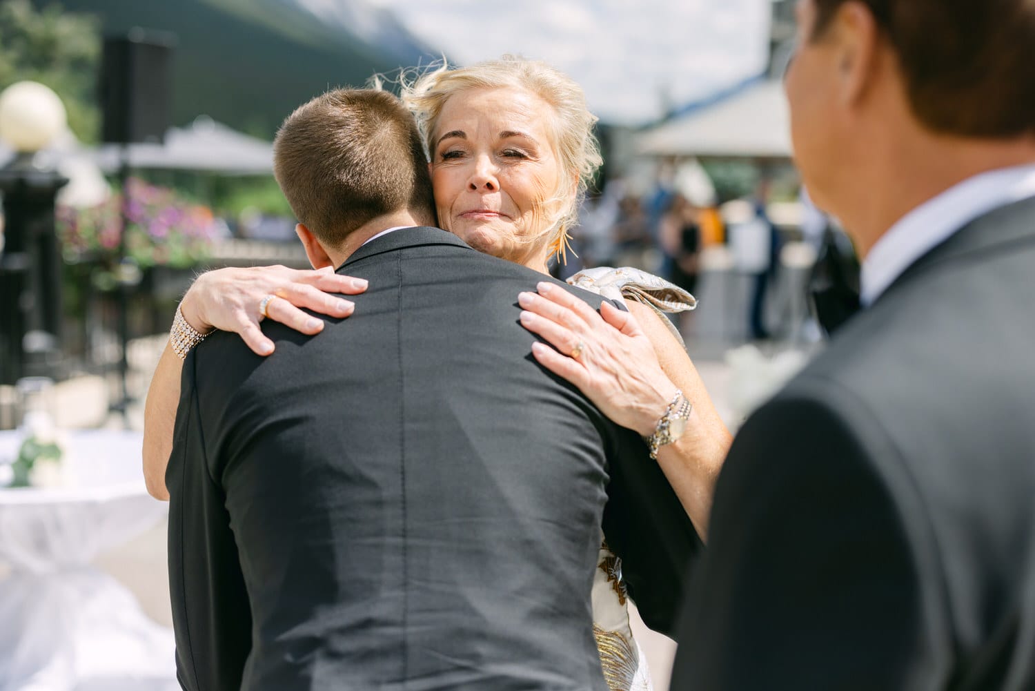 A woman embraces a man in formal attire, expressing joy and emotion during a festive outdoor event.