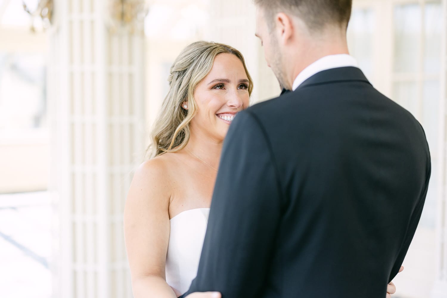 A bride smiles joyfully at her groom during an intimate moment at their wedding ceremony.