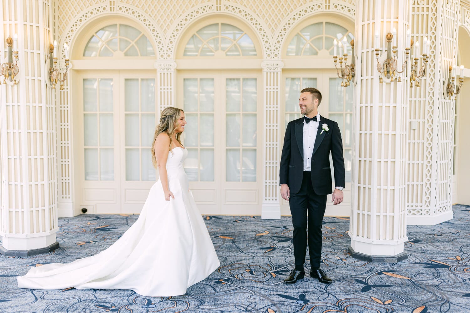 A joyful couple share an intimate moment during their first look before the wedding ceremony, set in an elegant indoor venue.