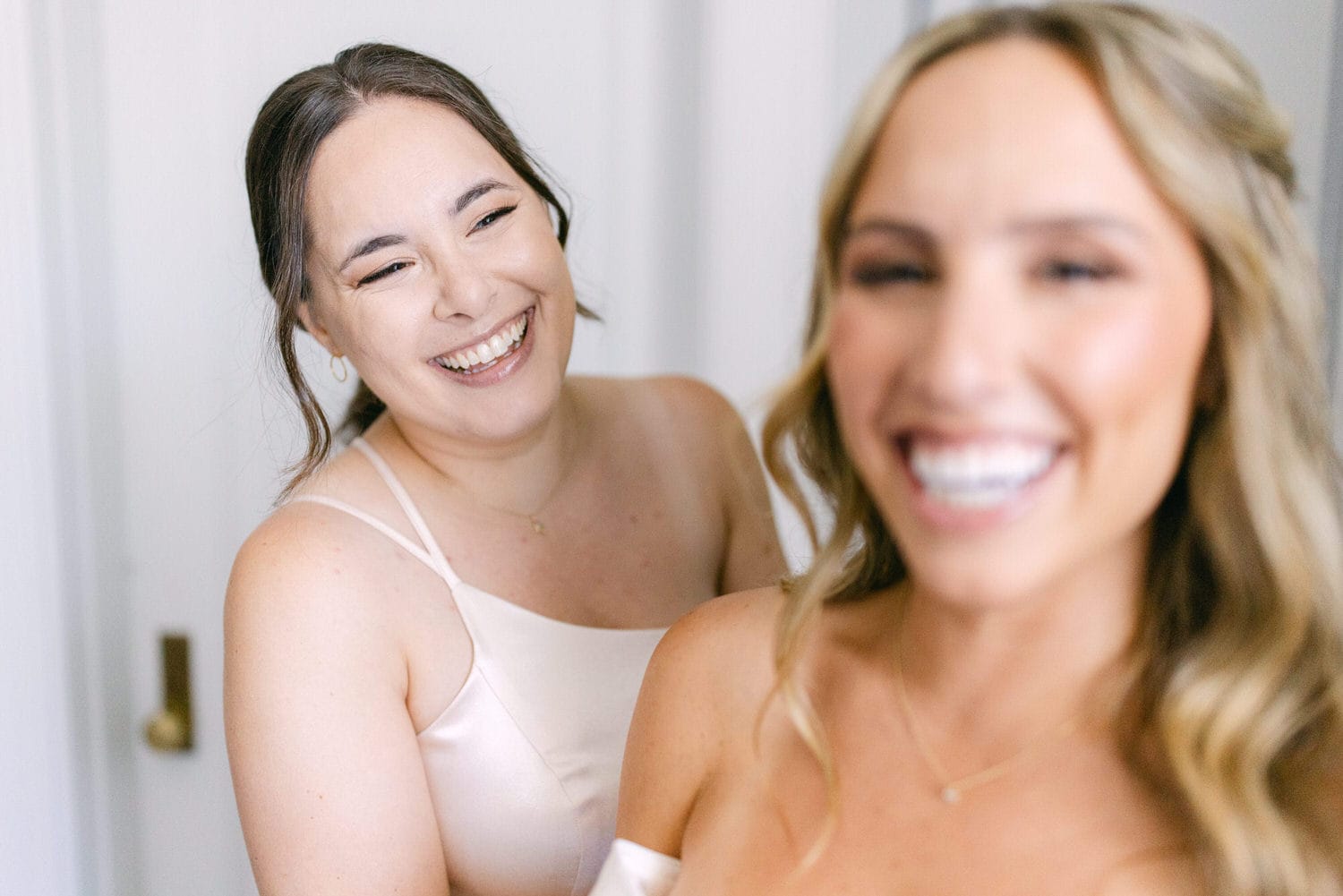 Two smiling friends share a lighthearted moment while getting ready, showcasing their happiness and camaraderie.