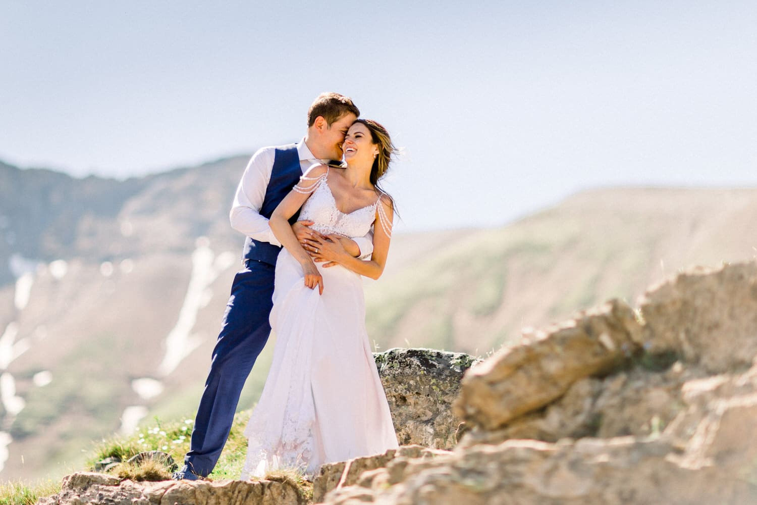 A joyful couple embraces against a breathtaking mountain backdrop during their wedding celebration.