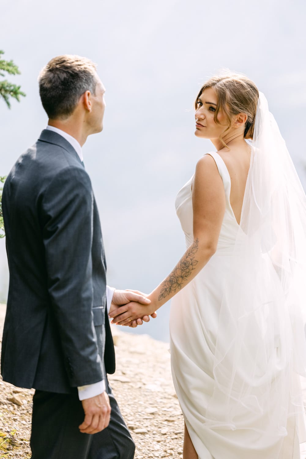 A bride and groom holding hands, gazing into each other's eyes against a misty background, showcasing love and connection on their special day.