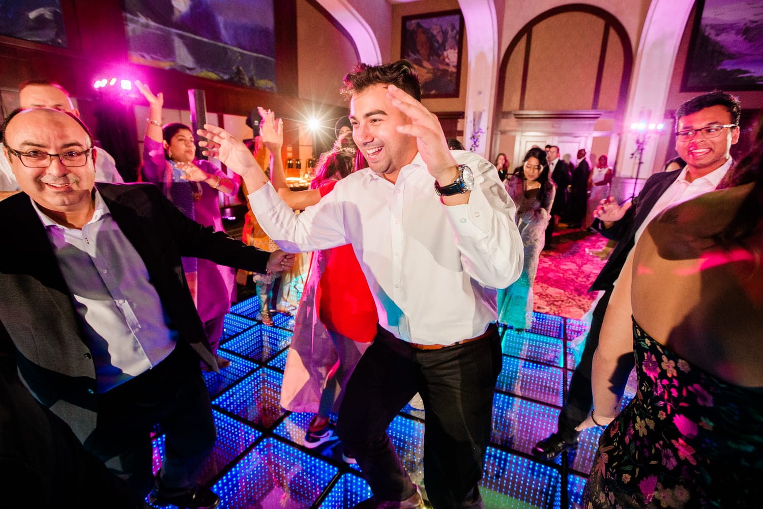 A lively dance floor scene featuring people joyfully dancing with colorful lights and a festive atmosphere.