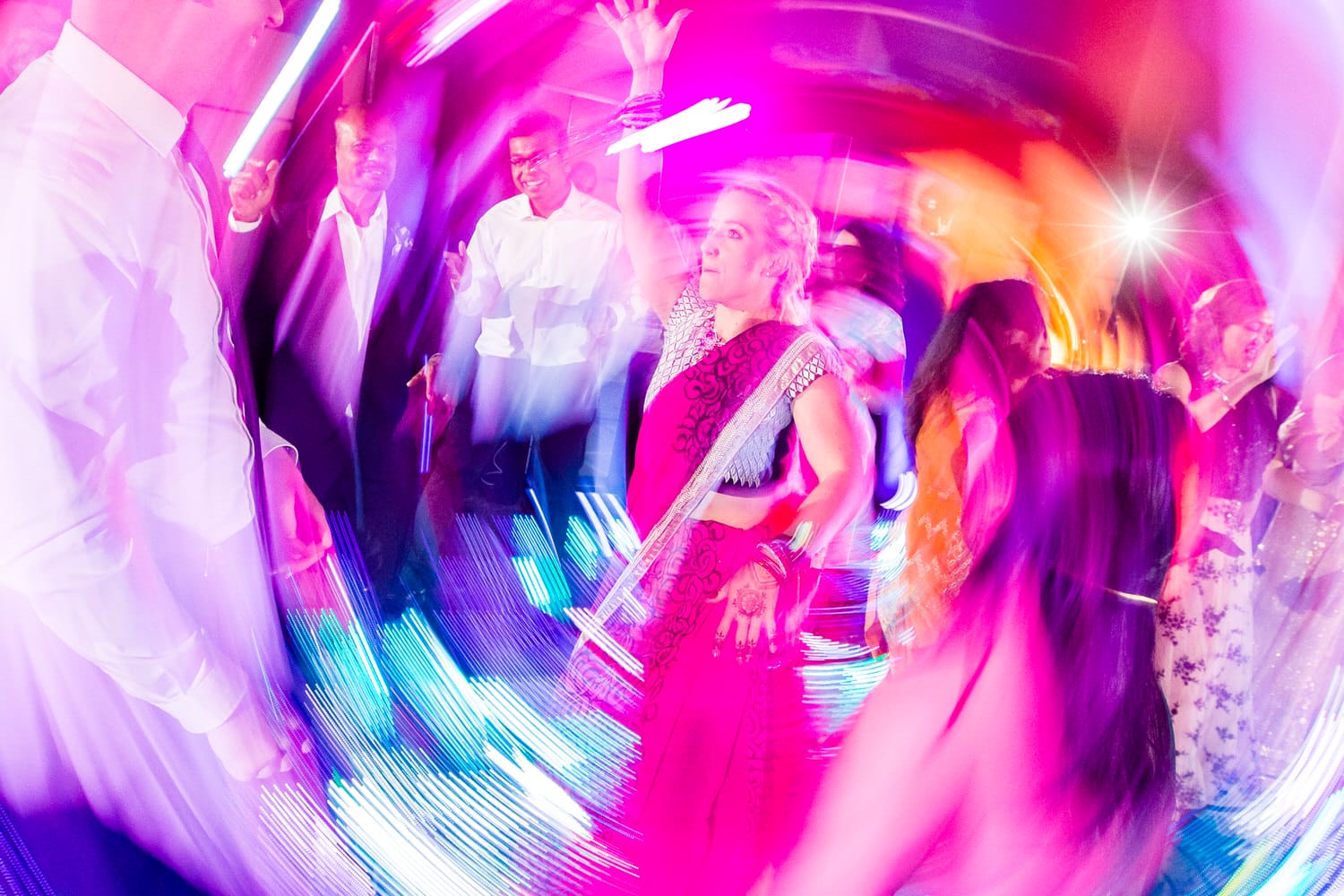 A lively dance scene showcasing individuals enjoying themselves in colorful attire under bright lights, creating a dynamic and festive atmosphere.