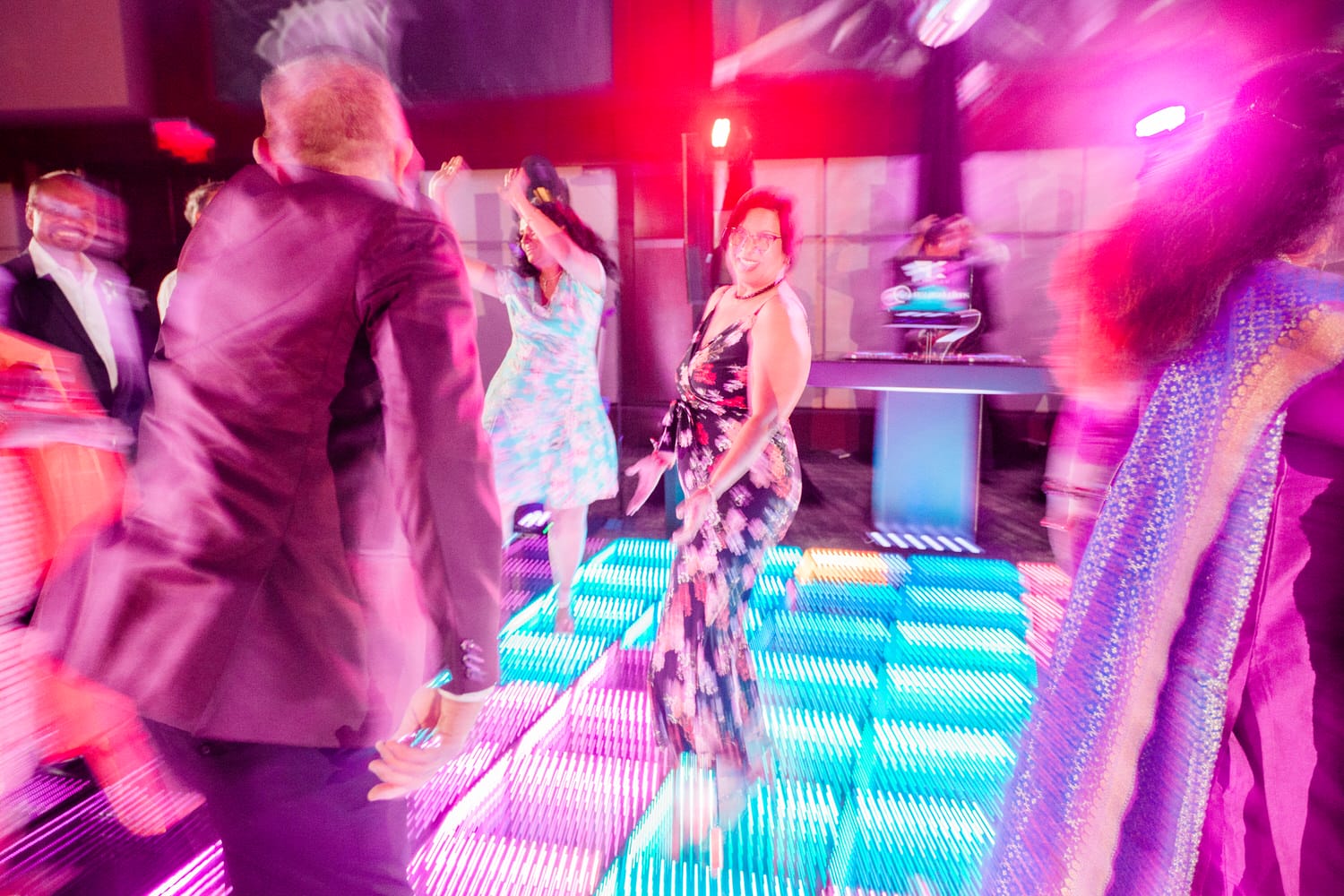 A lively dance floor scene with colorful lighting and people enjoying music at a celebration.