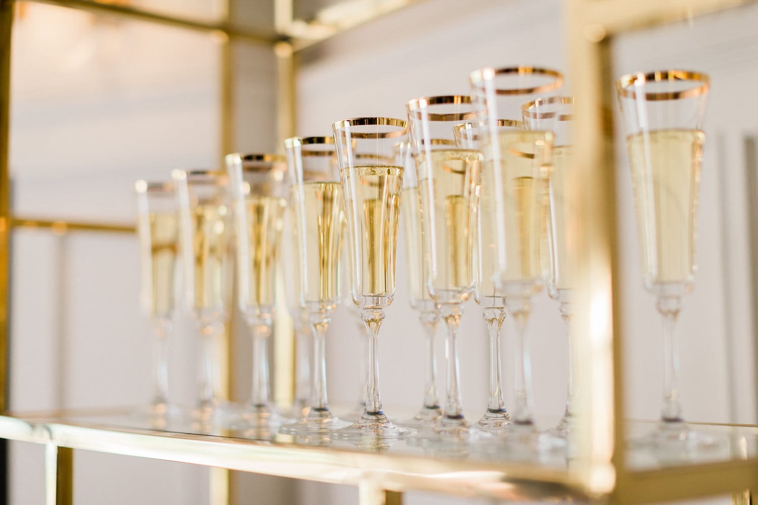 A collection of sparkling champagne flutes filled with golden liquid, elegantly arranged on a display stand with a golden frame.