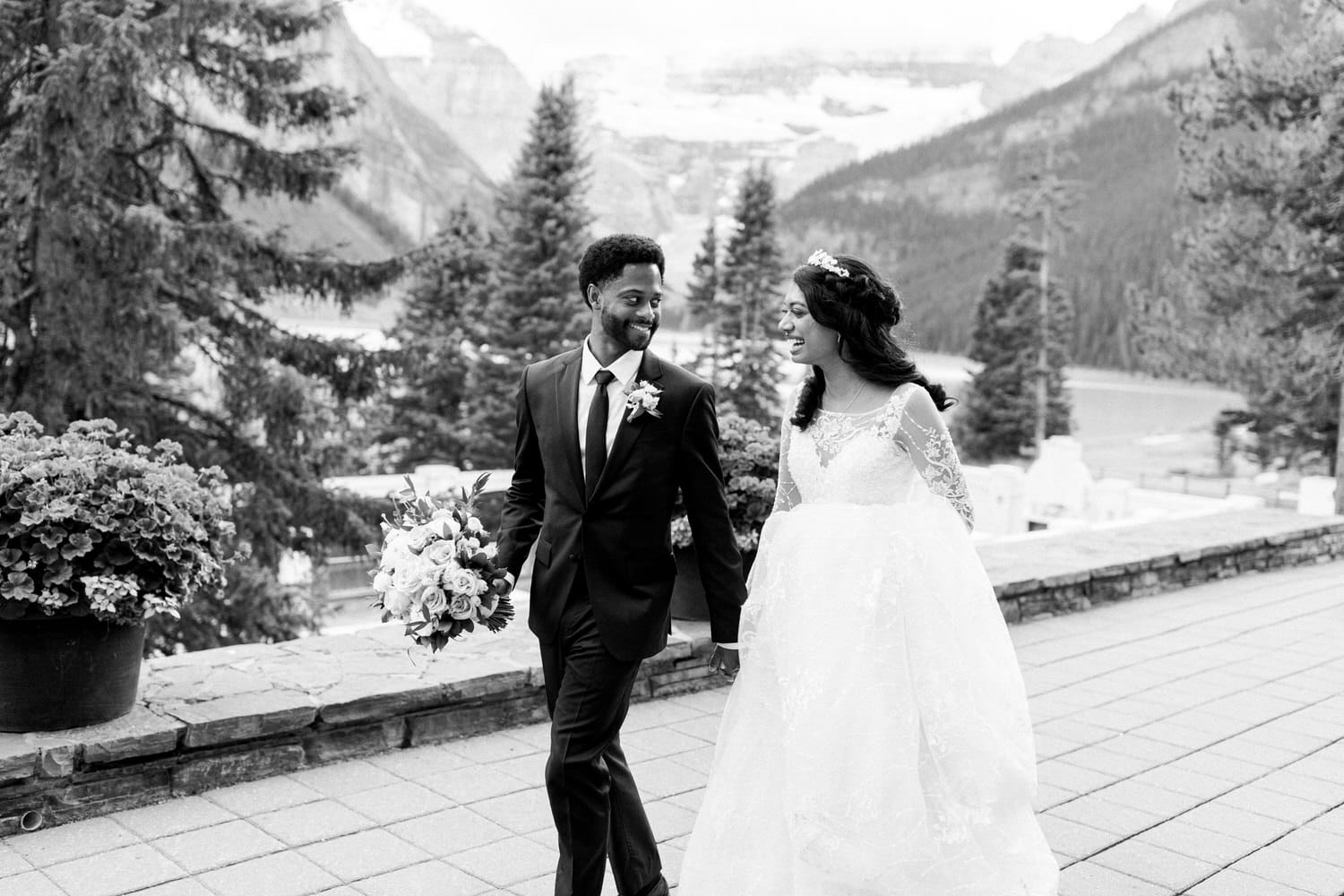 A joyful couple walks hand in hand, surrounded by stunning mountain scenery, capturing a moment of love and celebration on their wedding day.