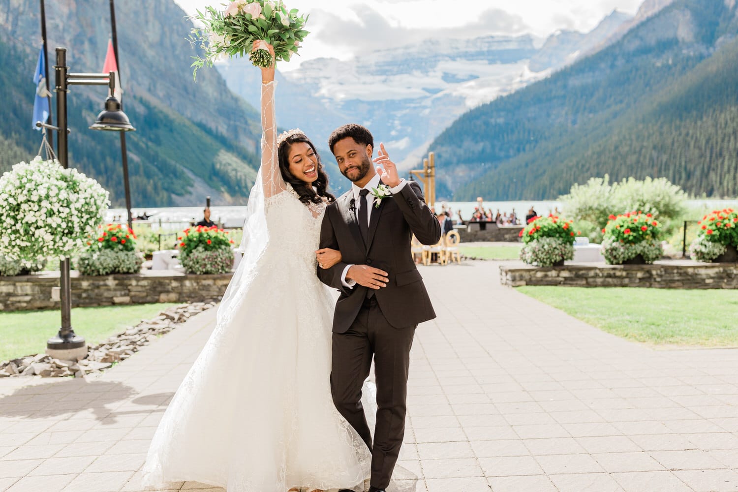 A couple celebrates their wedding outdoors, surrounded by stunning mountainous scenery and vibrant flower arrangements.