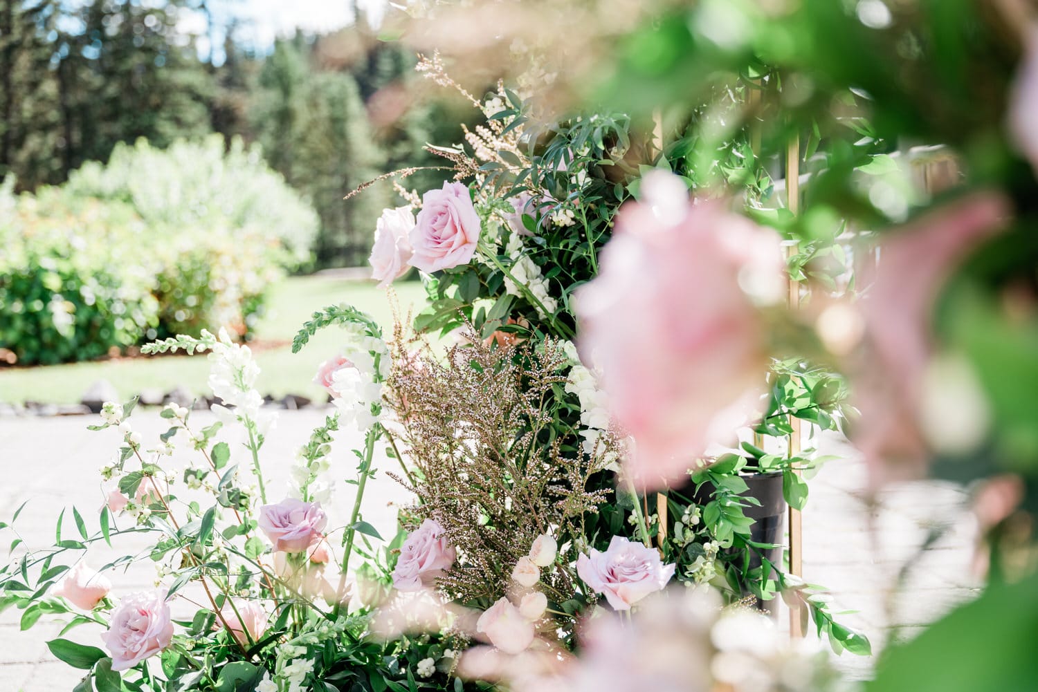 Close-up of a beautiful floral display featuring soft pink roses and assorted greenery in an outdoor setting.