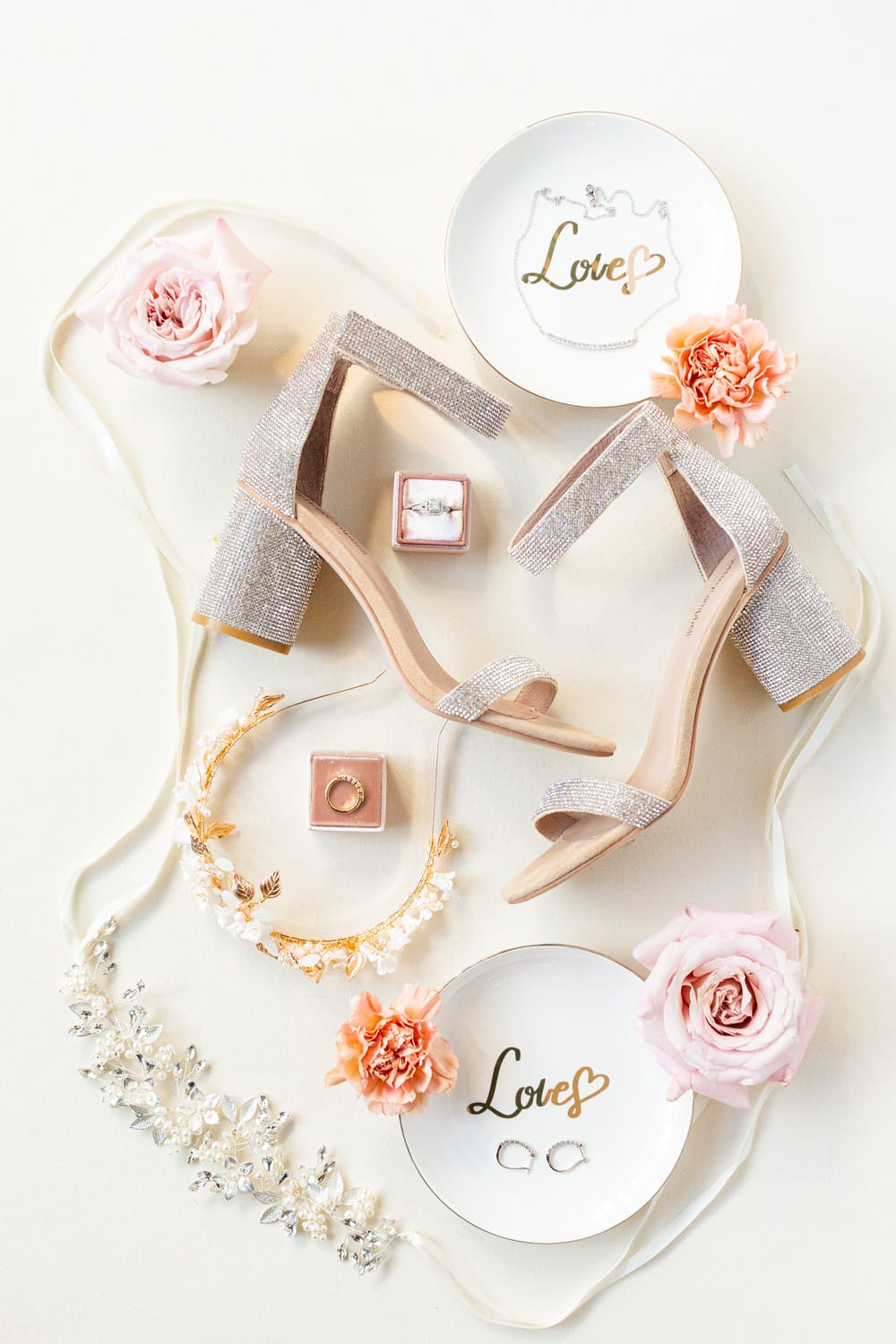 An elegant flat lay featuring sparkling heels, floral decor, and delicate jewelry on a soft background, perfect for a wedding inspiration.